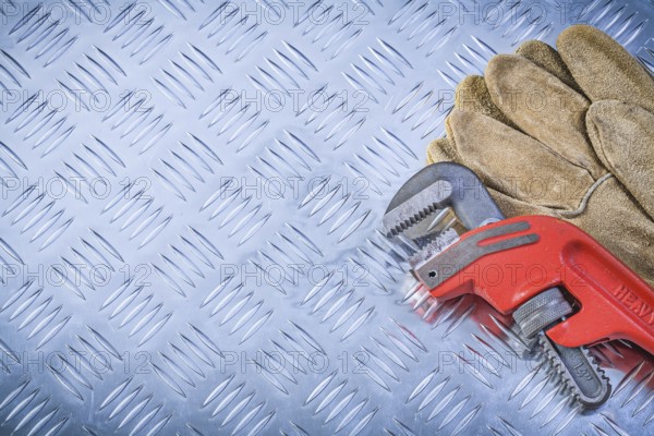 Pair of protective gloves pipe wrench on fluted metal sheet construction concept