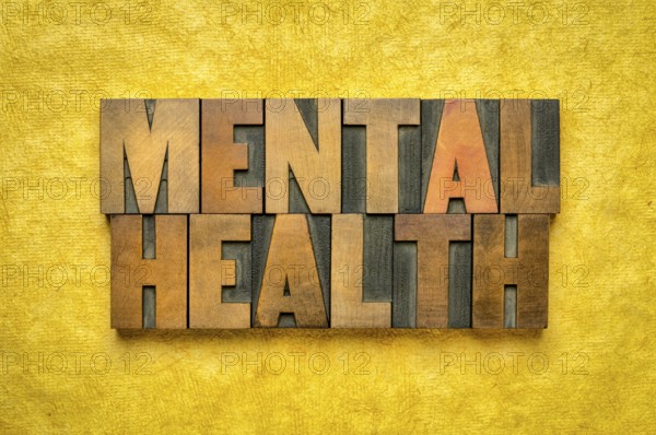 Mental health word abstract in vintage letterpress wood type printing blocks against yellow