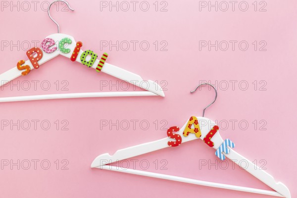 Creative top view flat lay white hangers special sale text pastel pink background copy space