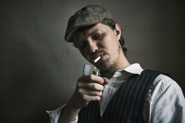 Young guy lights a cigarette, blows smoke, dressed in a retro style, in a beret, cinematic shot,