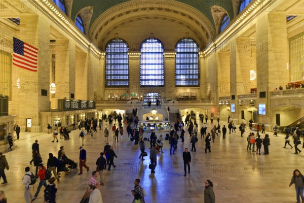 People moving through a large railway station concourse under a cool glow of light, Manhattan,