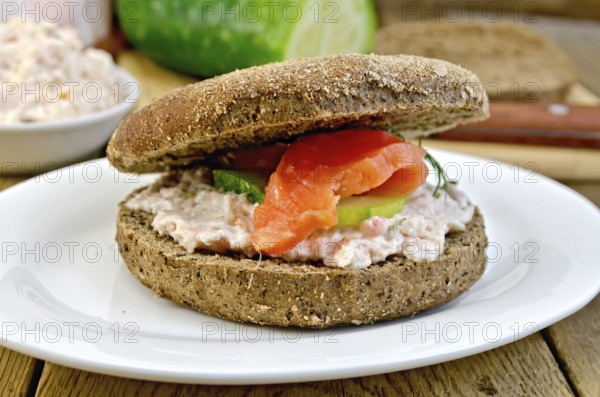Sandwich of rye bread with cream, cucumber, dill and salmon on a plate on a wooden boards