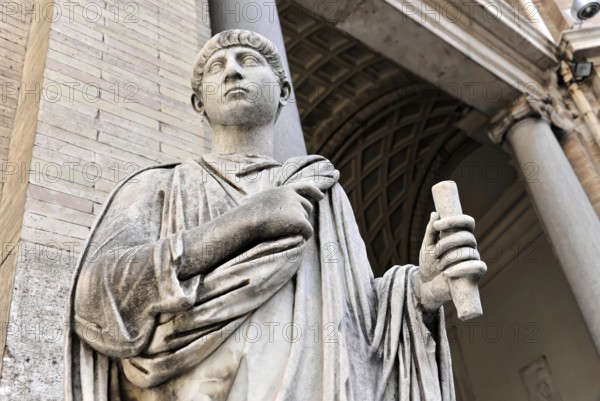Historical marble statue of a person holding a scroll in front of a classical column structure,
