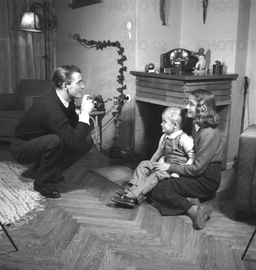 Amateur photographer in the 1940s A man is taking pictures of his wife and son at home. He is