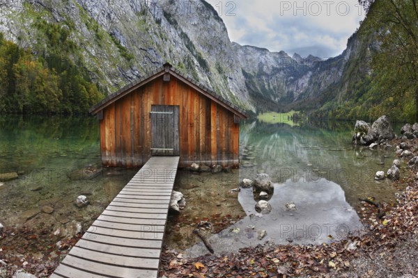 Cloudy day at Lake Koenigssee. Boathouse connected to the coast wooden decking. Clouds and