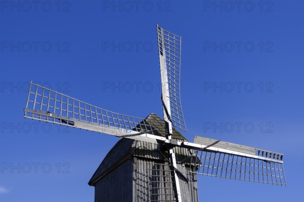 Windmill with wooden sails under a clear blue sky, traditional rural structure, borken,