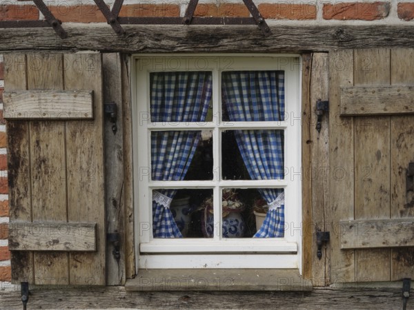 Rustic window with blue and white chequered curtains in a wooden frame, weseke, münsterland,