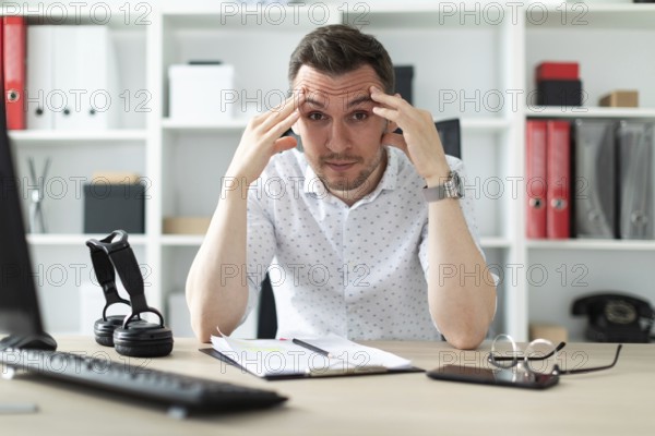 A young man in blue trousers and a light shirt. A handsome young man with a stubble on his face.