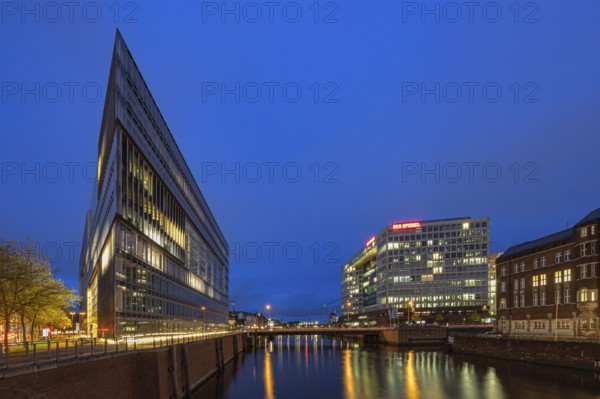 Modern office buildings reflect in the water at night, illuminated by numerous lights, Blue Hour,
