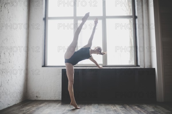 Plasticity slim woman dancing near window. Professional dancer enjoy dance. Lady Dancer Training
