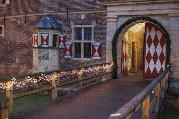 Castle bridge with lights leads to a large entrance gate, Rasfeld, Münsterland, North