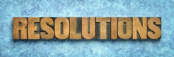 Resolutions word abstract in vintage letterpress wood type blocks against blue textured bark paper,