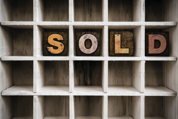The word SOLD written in vintage ink stained wooden letterpress type in a partitioned printer's