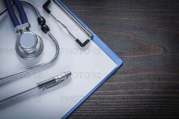 Clip board pen and stethoscope tablet on vintage wooden background medicine concept
