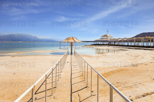 Railings enclose the path to the water. Lovely round umbrella protects from the sun. The drainless