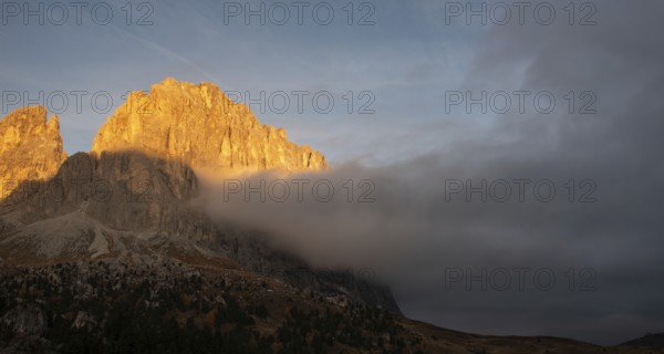 Foggy rocky mountain landscape at sunrise with blue sky. of the Dolomites at Passo Sella South