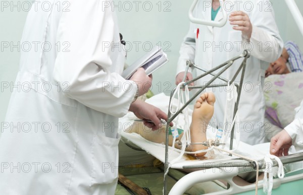 Group of surgeons examine patient with broken leg