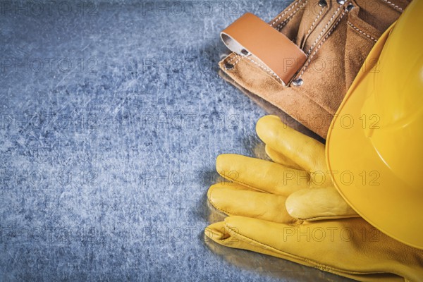 Safety gloves tool belt hard hat on metallic background construction concept