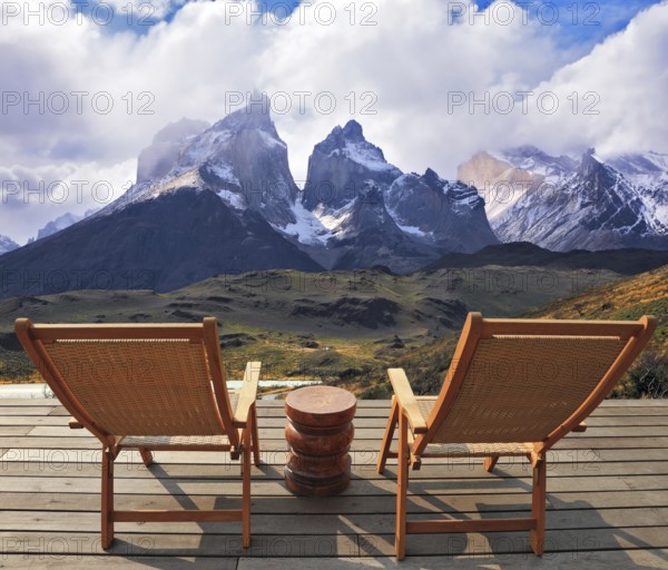 Comfortable lounge chairs on wooden platform for rest and observation. Gorgeous snow-covered rocks