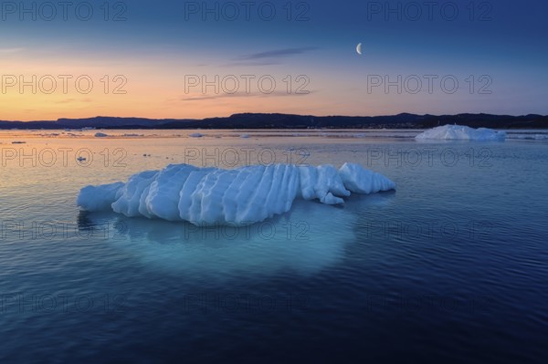 Floating glaciers in the rays of the setting sun at polar night with Moon