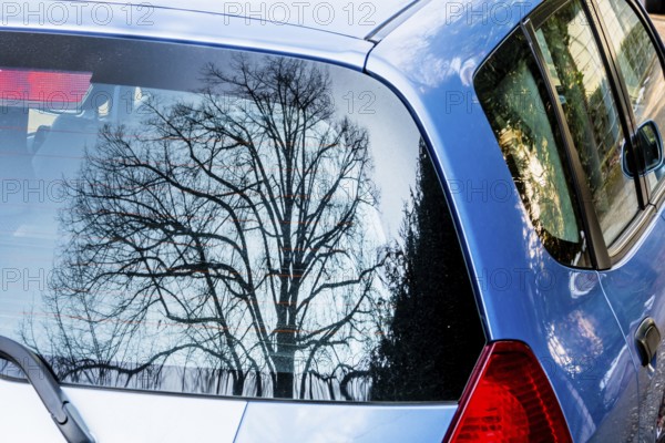 Baum spiegelt sich im Autofenster, Symbol für Natur und Technik, Kontrast, künstlich versus