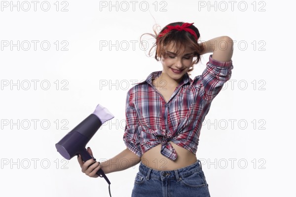A stylish and fashionable young woman is playfully and joyfully using a hair dryer, showcasing her