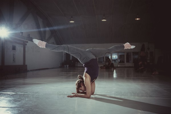 Young attractive yogi woman practicing yoga concept, standing in variation of Pincha Mayurasana