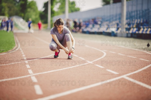 Theme sports and sportswear. A young Caucasian woman in uniform lacing shoelaces adjusting shoes