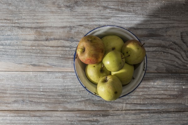 Apples in vintage metal cup on white wooden table