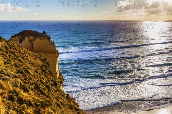 Powerful ocean surf at sunset. The Great Ocean Road. Steep and rocky ocean shore of Australia. The