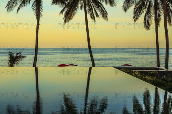 Delicate sunset on the popular resort island of Koh Samui. Palm trees reflected in smooth water of