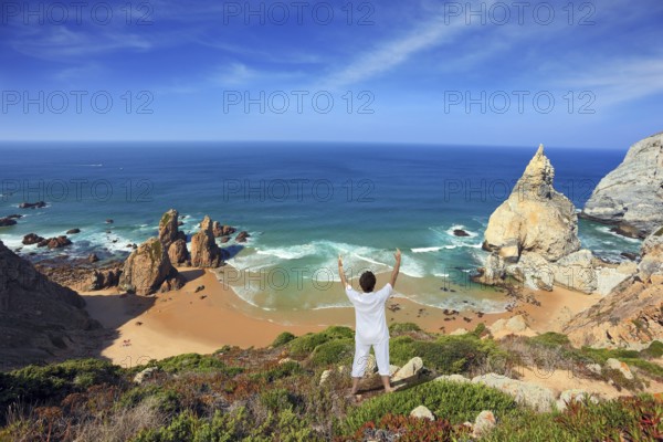 Small beautiful beach on the Atlantic coast. Middle-aged woman dressed in white doing yoga. The