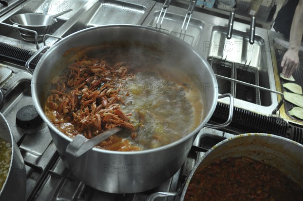 Shrimp boiling in a large pot on a stove in a busy kitchen setting, Cooks and chefs prepare dinner