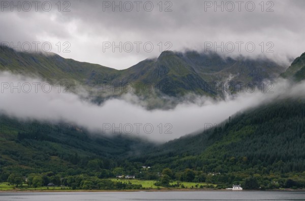 Idyllic mountain landscape with morning early fog covering the peaks at Fort Williams, Glencoe area