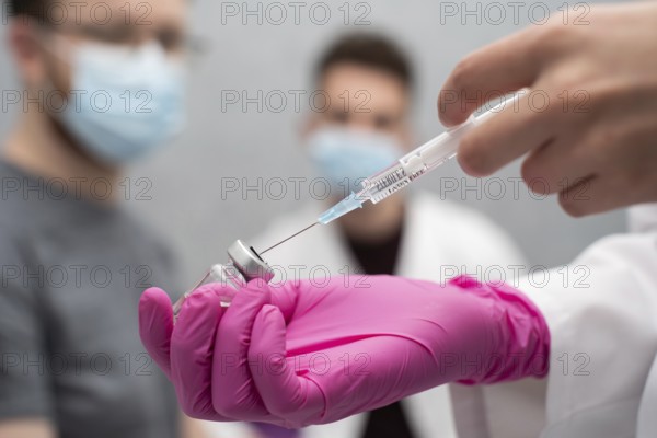 In a practical lesson, a young nurse shows medical trainees how to correctly draw a medicine from a