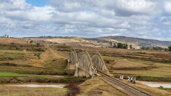 Malagasy people from the countryside cross a railroad bridge on the way to work and school on May