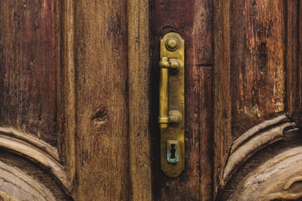 Vintage background. Brass-made old handle with Elements of an carved wooden door decorated with