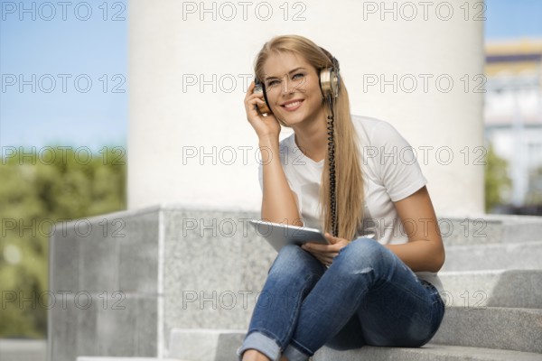 Happy young woman listening to music with vintage headphones, surfing the internet on a tablet PC