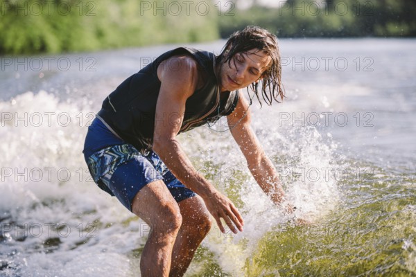 Active wakesurfer jumping on wake board down the river waves. Surfer on wave. Male athlete training