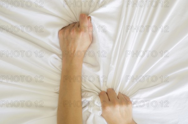 Hand sign orgasm of woman on white bed, Hand of female pulling white sheets in ecstasy, feeling and