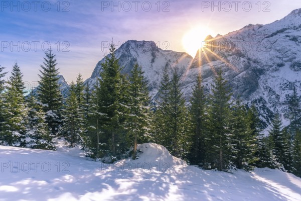 Serene winter landscape with a bright sun shining over the peaks of the Austrian Alps and its