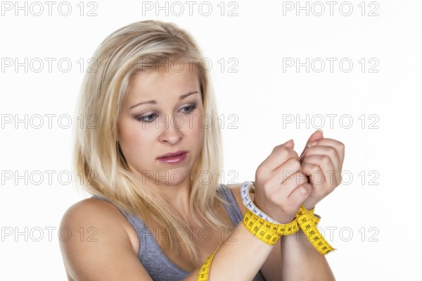 A young woman with a measuring tape in front of her next diet. Losing weight and fasting