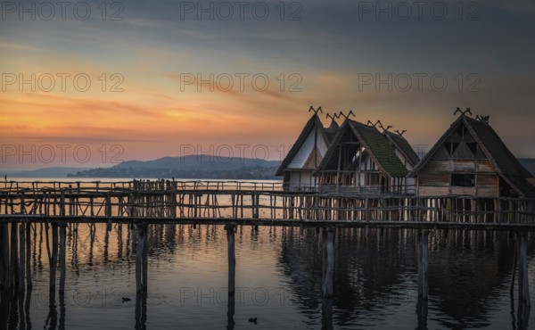 Weathered wooden cabins built on wooden pillars over the Bodensee lake water, at colorful sunset,