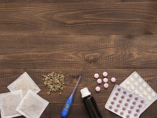 Tablets, drops, herbals and thermometer on a dark wooden background with copy space. Herbal