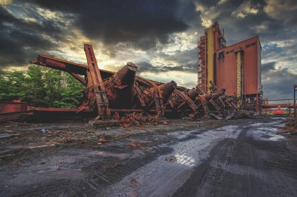 Dilapidated agricultural facility with a silo at sunset under dark clouds, HF6, Lost Place,