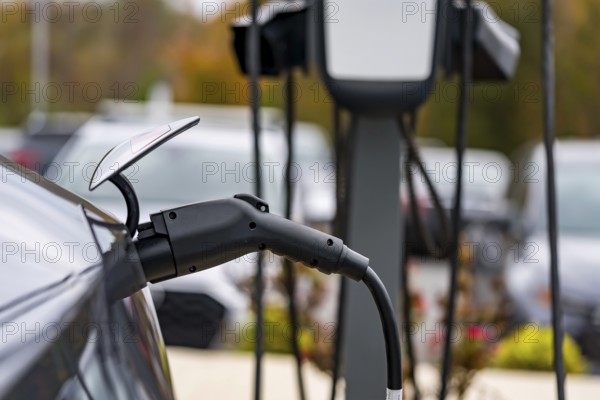 An electric vehicle recharges at a station while its owner is at work, allowing for a fully charged