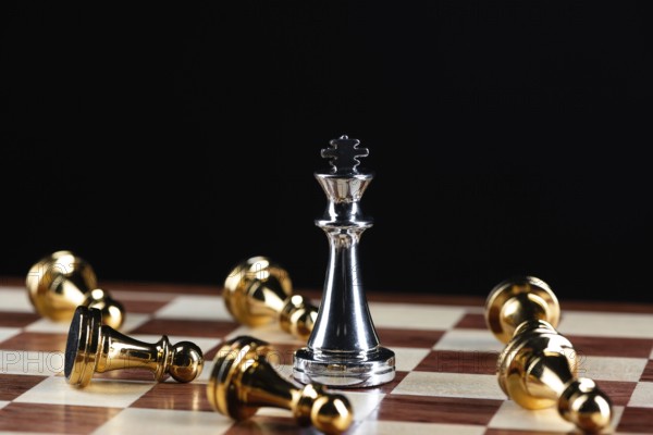 Silver king chess defeats gold pawns on wooden chessboard. Intellectual duel and tactical battle in