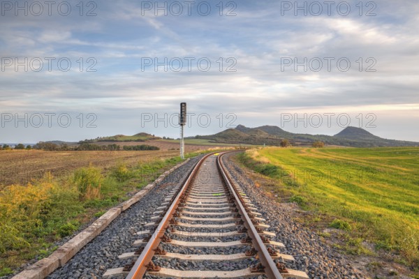 Old Railway tracks running through a field stretch to rural countryside at sunset. Single railway