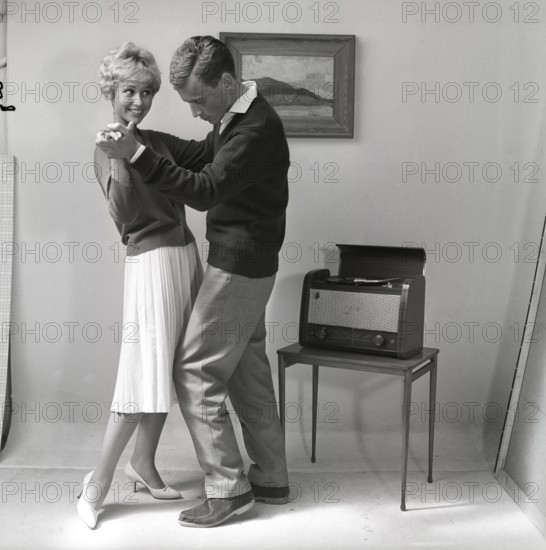 Learning to dance in the 1950s. A young copule is dancing in a photographers studio. The young