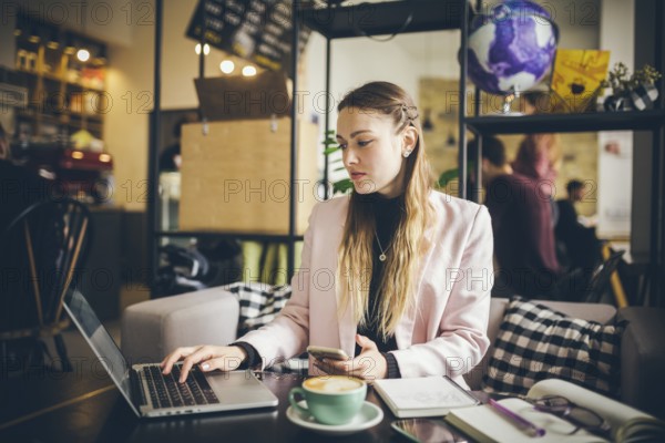 Business woman freelance working on computer notebook laptop and mobile phone, with coffee cup on